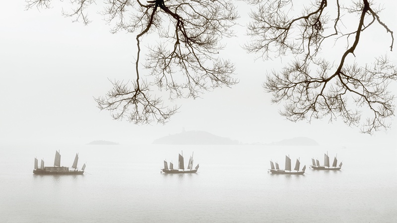 hk_c_太湖黿頭渚，煙雨朦朧，遠處的三山隱約可見，湖中的帆船停泊在水中央，構成一幅水墨山水畫卷。張建中.jpg
