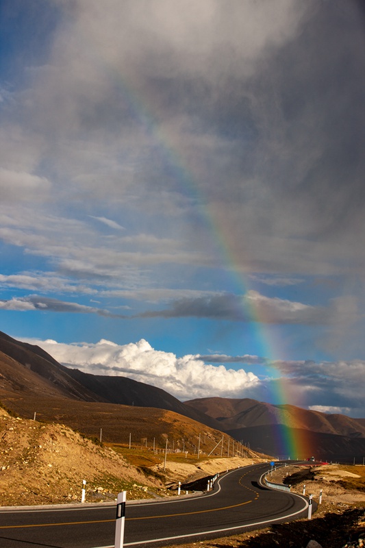 hk_c_自駕西藏途經川西理塘時，對流雲團局部降雨形成彩虹，與318國道彎曲的路面構成一幅美麗的畫卷。 周昌發.jpg